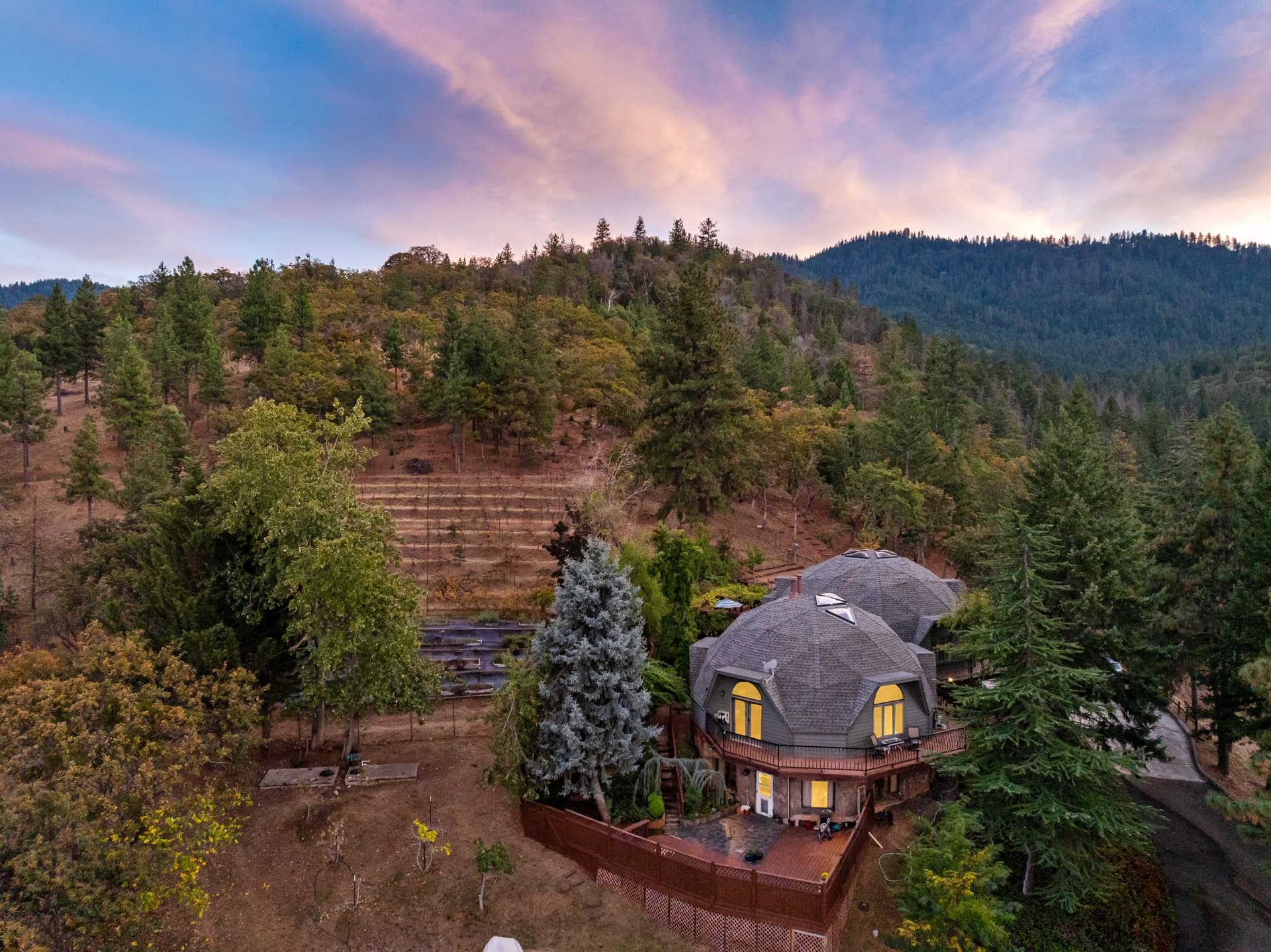Aerial twilight view of the estate, orchard terraces, and forested ridge