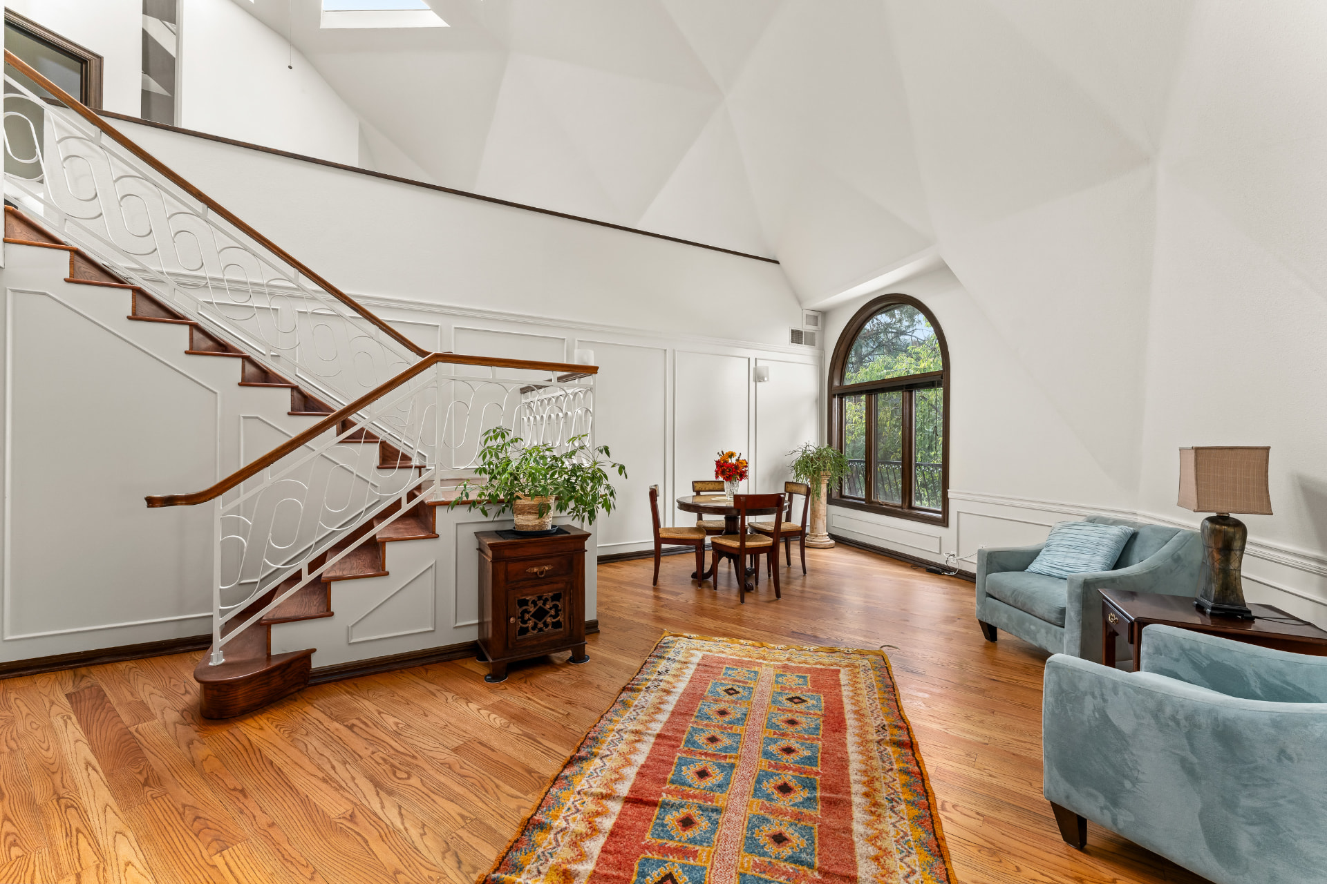 Bright main-level sitting area and staircase beneath the faceted ceiling