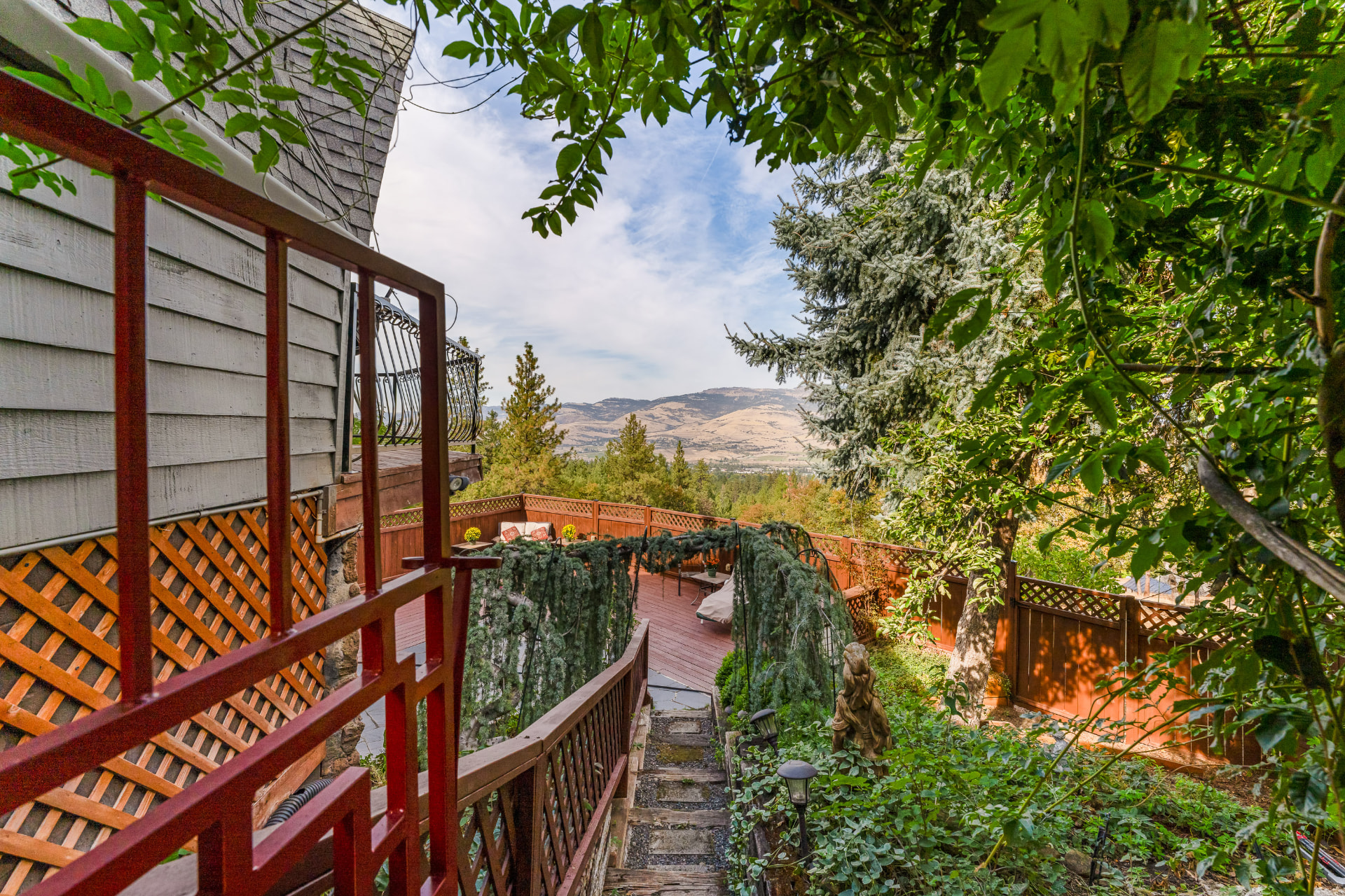 Wooded garden path and deck stairs opening toward the mountain view