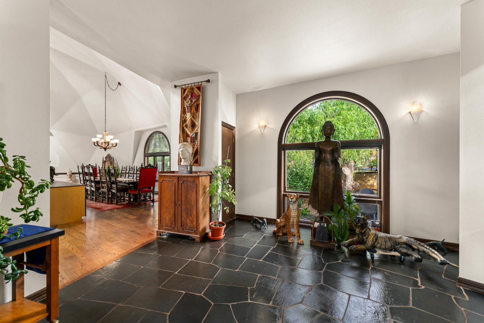 Slate-floored entry gallery with an arched window and sculpture collection