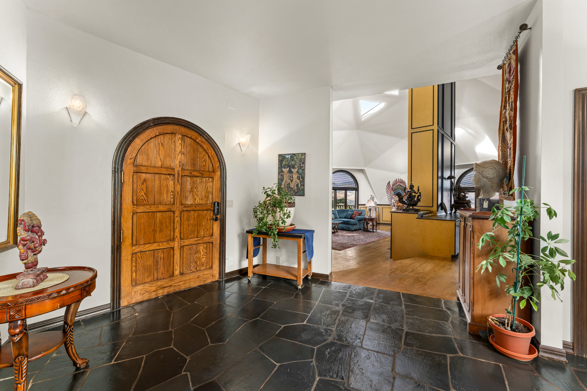 Slate-floored entry with an arched wood door opening toward the main geodesic living space