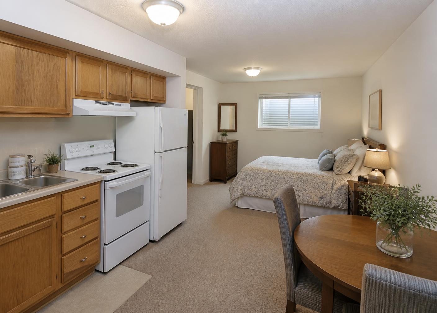 Self-contained lower-level apartment with oak-cabinet kitchenette, dining nook, and bed